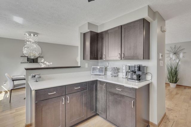 kitchen featuring light countertops, dark brown cabinets, light wood-style floors, and a peninsula