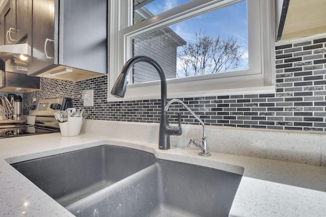 details featuring light stone counters, dark brown cabinets, backsplash, and a sink