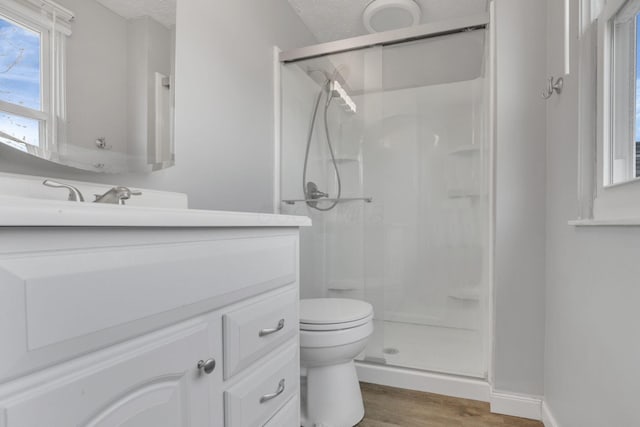 full bathroom featuring toilet, a stall shower, wood finished floors, a textured ceiling, and vanity