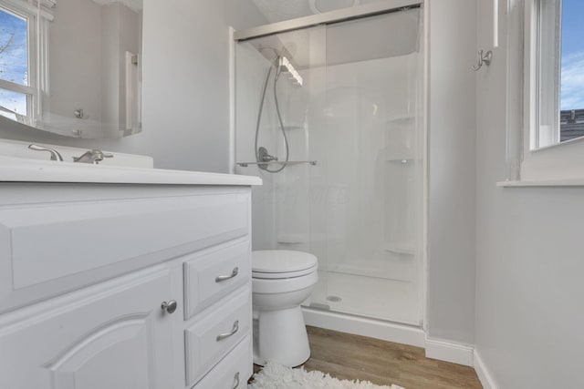 full bathroom featuring baseboards, toilet, a stall shower, wood finished floors, and vanity