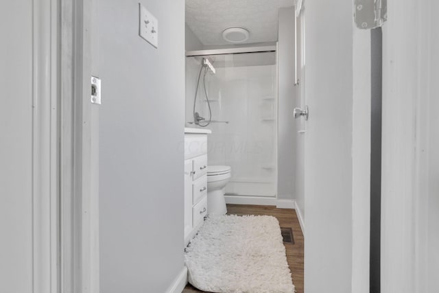 bathroom featuring visible vents, toilet, a stall shower, a textured ceiling, and wood finished floors