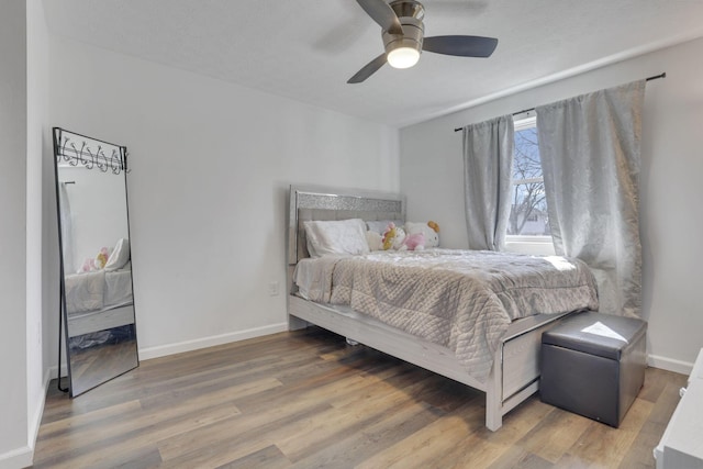 bedroom with a ceiling fan, wood finished floors, and baseboards