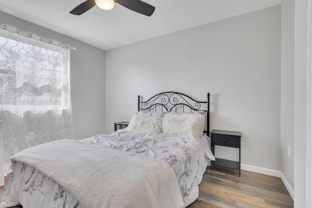 bedroom featuring baseboards, a textured ceiling, wood finished floors, and a ceiling fan