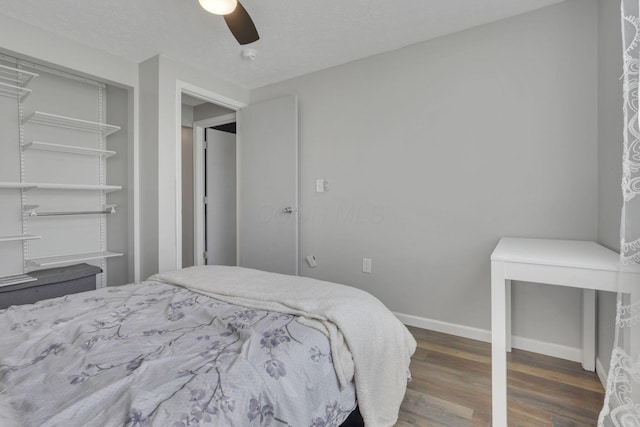 bedroom featuring a ceiling fan, wood finished floors, baseboards, a closet, and a textured ceiling