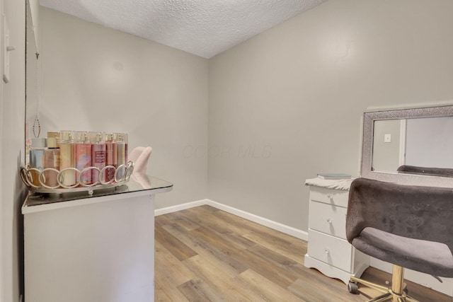 home office with light wood-style floors, baseboards, and a textured ceiling