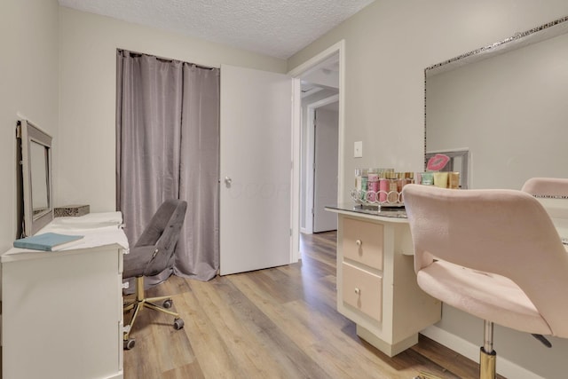 home office featuring light wood-type flooring and a textured ceiling