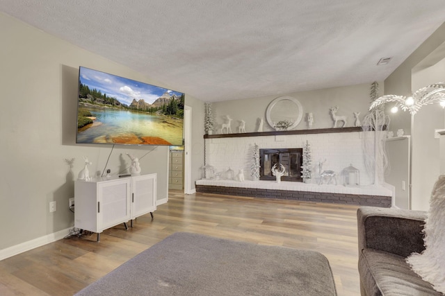 living room with wood finished floors, a fireplace, baseboards, and a textured ceiling