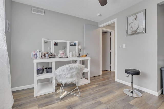 office featuring a ceiling fan, wood finished floors, visible vents, and baseboards