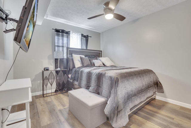 bedroom with baseboards, a textured ceiling, and wood finished floors