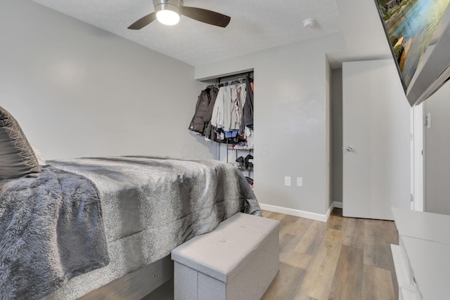 bedroom with ceiling fan, wood finished floors, baseboards, and a textured ceiling