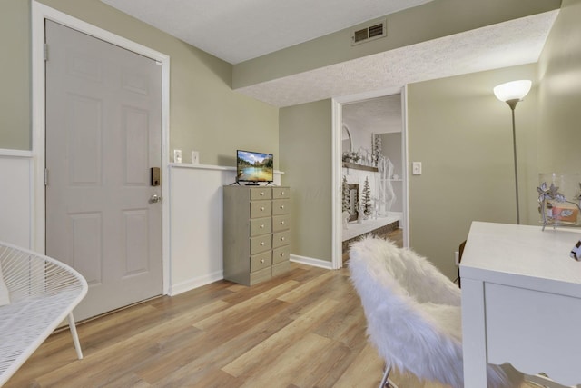 bathroom with visible vents, baseboards, a fireplace, wood finished floors, and a textured ceiling