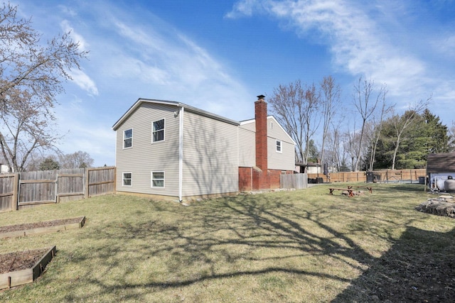 view of side of property with a lawn, a chimney, and a fenced backyard