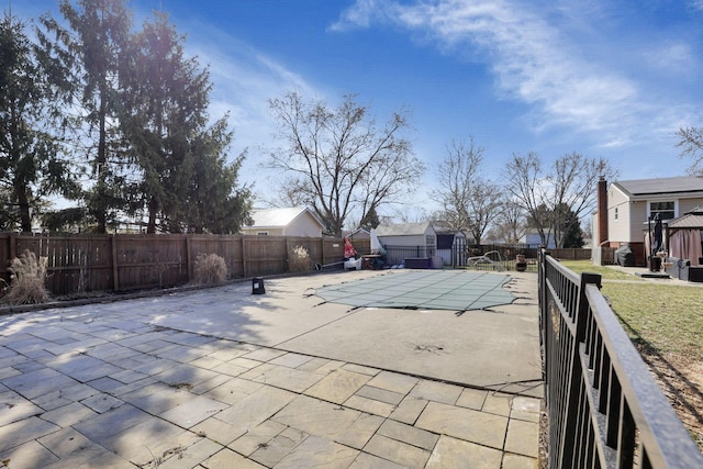 view of swimming pool featuring an outdoor structure, a patio area, a fenced in pool, and a fenced backyard