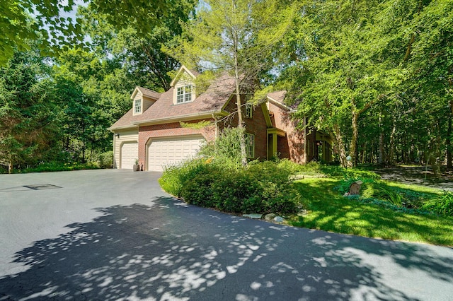 view of side of property with a garage, brick siding, and driveway