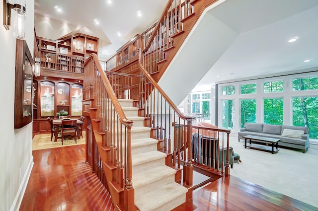 staircase featuring recessed lighting, a high ceiling, and hardwood / wood-style floors