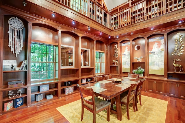 dining room with track lighting, a towering ceiling, and wood finished floors