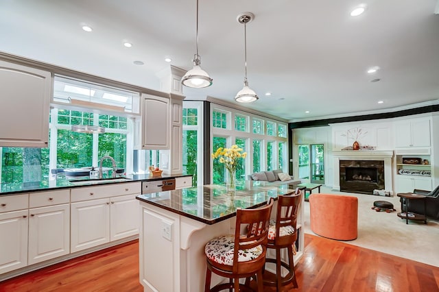 kitchen featuring a high end fireplace, open floor plan, light wood finished floors, and pendant lighting