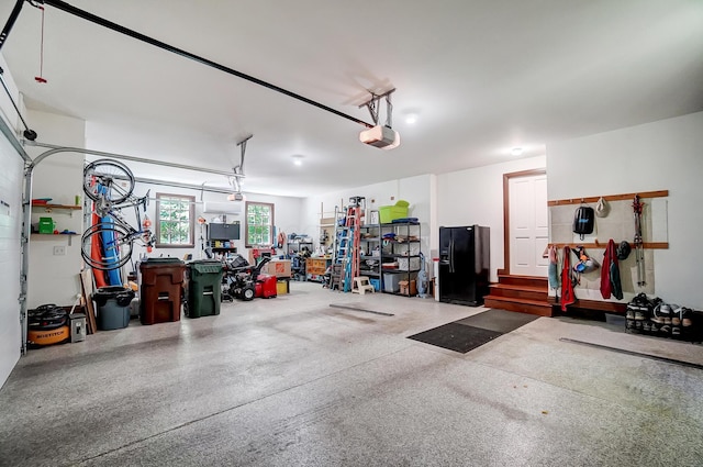 garage with a workshop area, a garage door opener, and black fridge