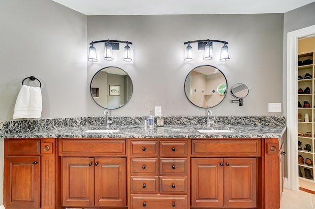 full bath featuring double vanity, a walk in closet, and a sink