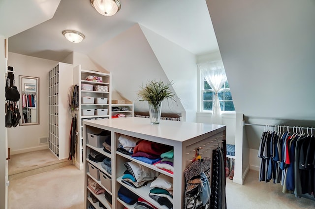 walk in closet featuring visible vents, light carpet, and vaulted ceiling