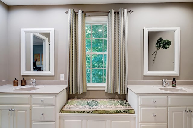 bathroom with a healthy amount of sunlight, two vanities, and a sink