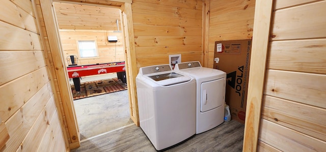 washroom with washer and dryer, wooden walls, wood finished floors, and laundry area