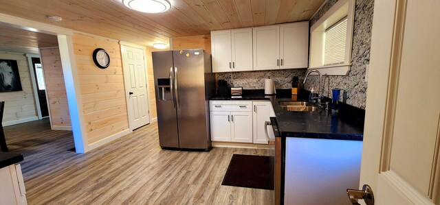 kitchen with stainless steel fridge, wooden ceiling, white cabinetry, and a sink