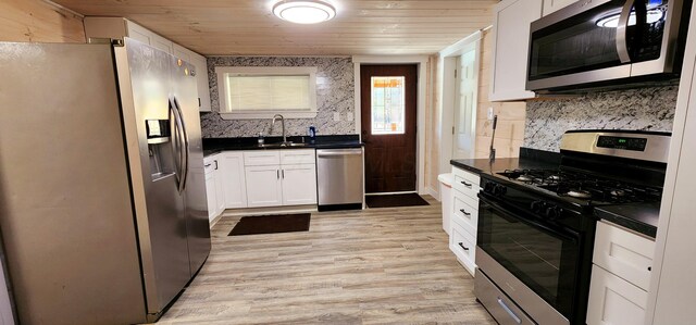 kitchen with a sink, dark countertops, appliances with stainless steel finishes, and wooden ceiling