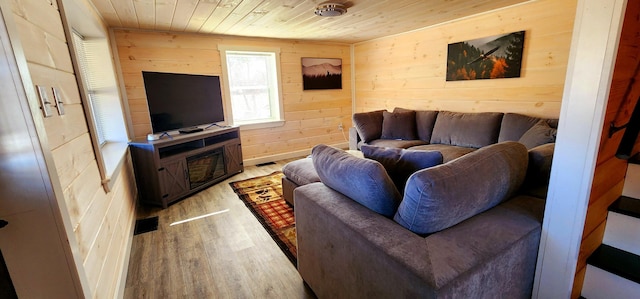 living room with visible vents, light wood-style floors, wood ceiling, and wood walls