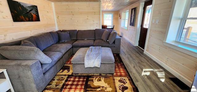 living area with wooden walls, wood ceiling, baseboards, and wood finished floors