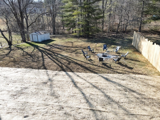 view of yard featuring an outdoor fire pit, a storage shed, an outdoor structure, and fence