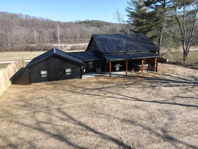 exterior space featuring driveway, fence, cooling unit, metal roof, and an attached carport