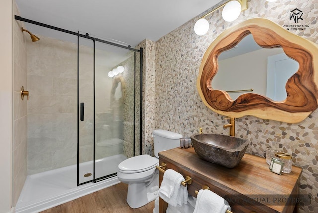 bathroom with vanity, toilet, wood finished floors, and a shower stall