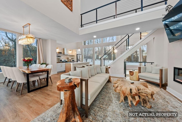 living room with a glass covered fireplace, light wood-style flooring, stairs, and a healthy amount of sunlight