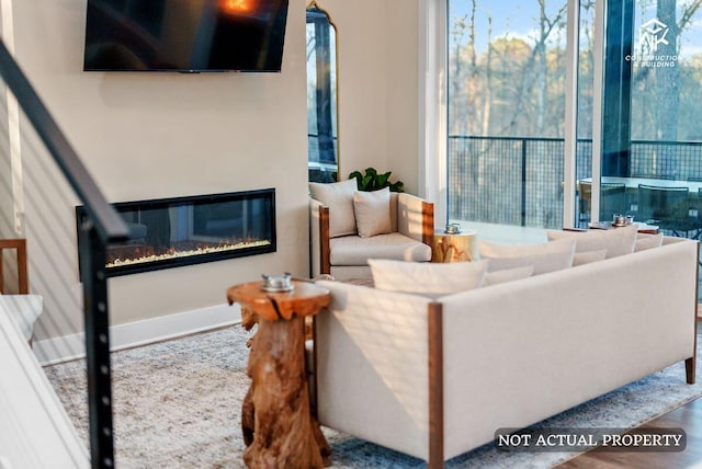 living area with a glass covered fireplace, wood finished floors, and baseboards