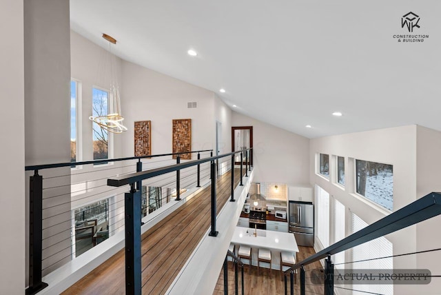 staircase with visible vents, recessed lighting, wood finished floors, and vaulted ceiling