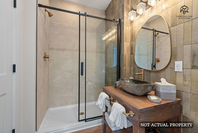 full bath with a stall shower, tile walls, and vanity