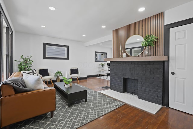 living room featuring a brick fireplace, recessed lighting, and wood finished floors