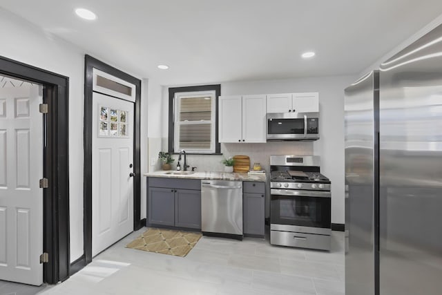 kitchen with recessed lighting, appliances with stainless steel finishes, gray cabinets, white cabinetry, and a sink