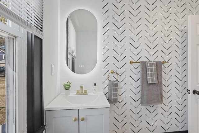 bathroom with an accent wall, vanity, and wallpapered walls