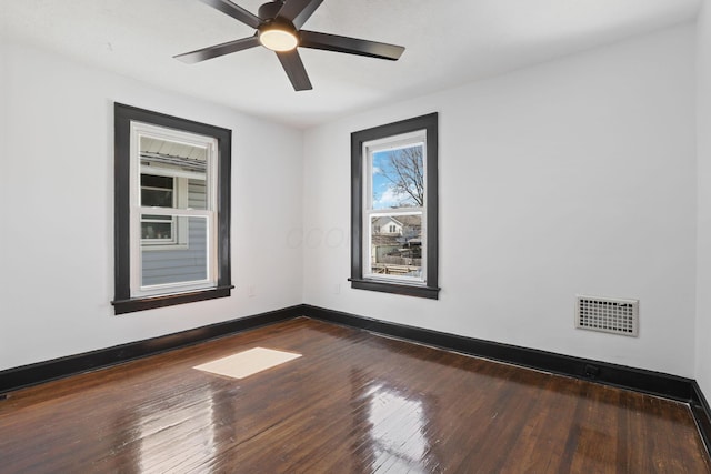 empty room with ceiling fan, visible vents, baseboards, and dark wood finished floors