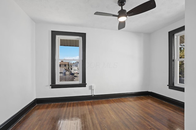 spare room featuring ceiling fan, baseboards, wood-type flooring, and a textured ceiling