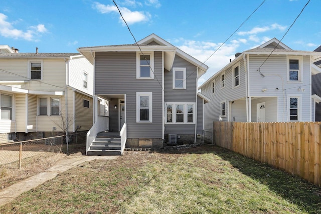 rear view of house with a yard, central AC, and fence private yard