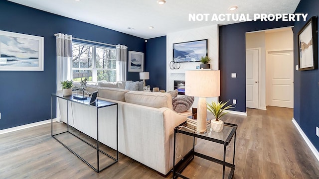 living room with baseboards, wood finished floors, and a high end fireplace