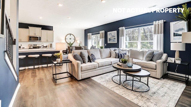 living room featuring recessed lighting, light wood-style floors, visible vents, and baseboards