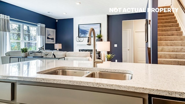 kitchen with open floor plan, recessed lighting, light stone countertops, and a sink