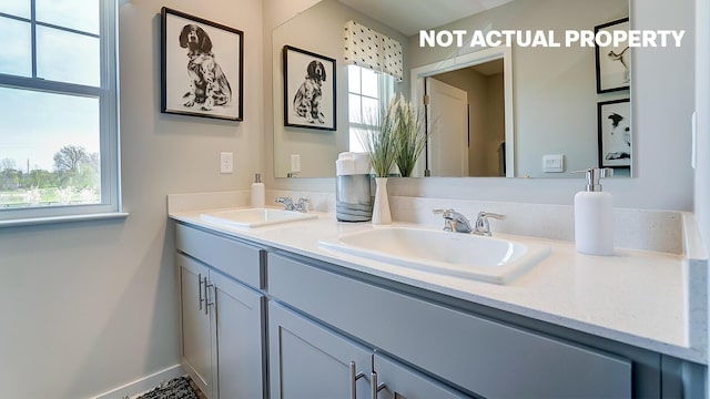 full bathroom with double vanity, baseboards, and a sink