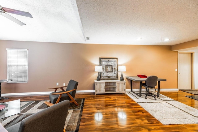 living area featuring baseboards, a textured ceiling, wood finished floors, and a ceiling fan