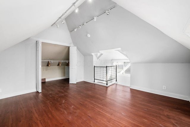 additional living space with baseboards, wood finished floors, and vaulted ceiling