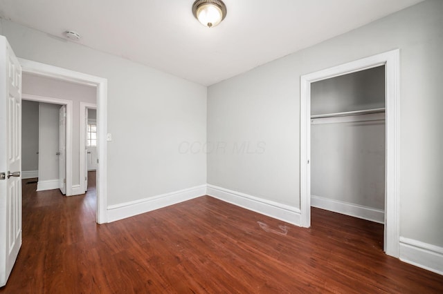 unfurnished bedroom with a closet, baseboards, and wood finished floors